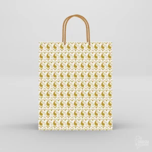 White paper gift bag decorated with repeating gold mango paisley motifs and twisted golden rope handles.
