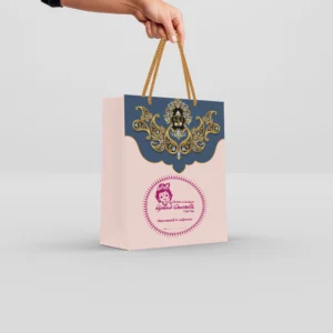 Customized thamboolam bags in blush pink and royal blue with jeweled Ganesha artwork and braided gold rope handle.
