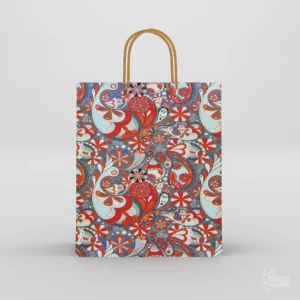 Paisley wedding thamboolam bags featuring red and teal motifs with twisted gold rope handle on grey backdrop